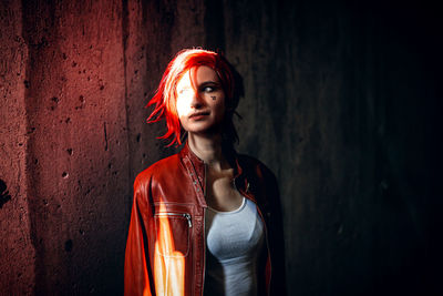 Young woman standing against wall