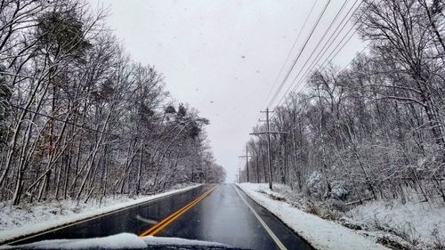 Road amidst bare trees against clear sky during winter