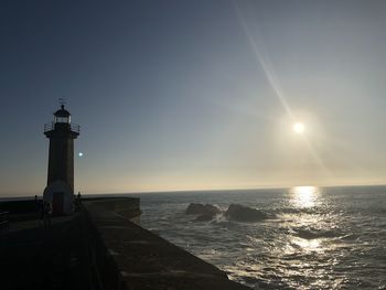 Lighthouse by sea against sky