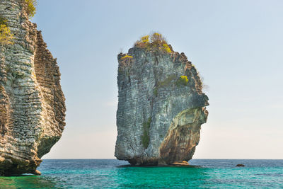 Rock formation in sea against clear sky