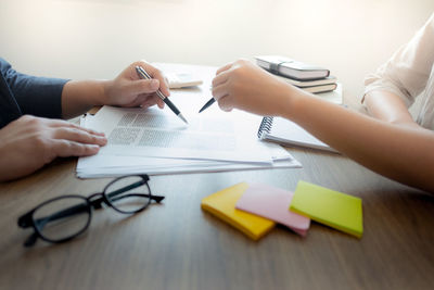 Midsection of woman holding paper with text on table