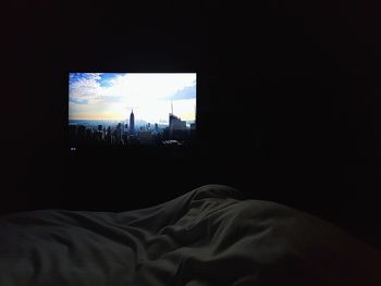 Silhouette of man relaxing on bed against window at home