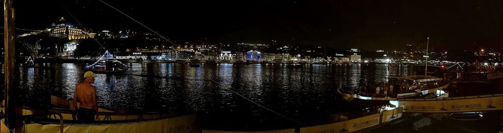 Illuminated harbor by river against sky at night