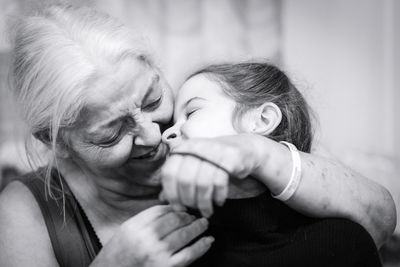 Close-up of grandmother embracing granddaughter at home