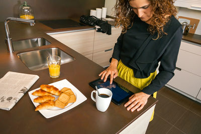 Midsection of woman holding coffee cup at home