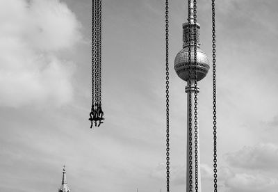 Low angle view of fernsehturm seen through chains against sky