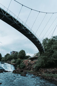 Low angle view of bridge over river against sky