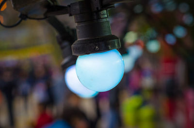 Close-up of blue light bulbs hanging outdoors