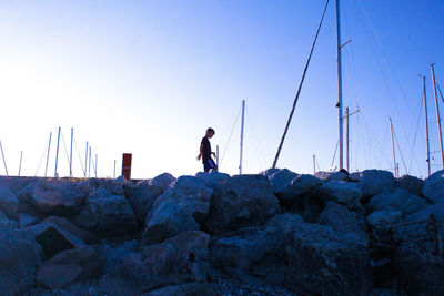 Rear view of man fishing on rock against sky