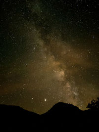 Low angle view of silhouette mountain against sky at night