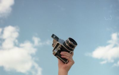 Low section of person holding camera against sky