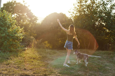 Side view of woman with dog on grassy field