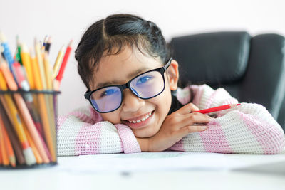 Portrait of smiling boy with book on table