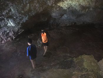 Rear view of men walking on rock by sea