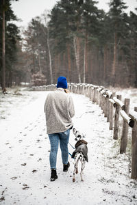 Rear view of man walking on snow covered field