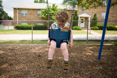 Toddler boy sitting on swing at park