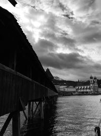 Bridge over river by buildings against sky