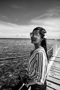 Woman wearing sunglasses against sea against sky