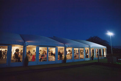 People against illuminated blue sky at night