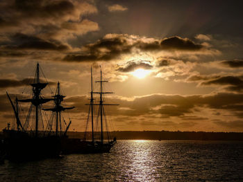 Sailboats in sea against sky during sunset