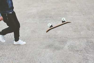 Low section of man with skateboard walking on footpath