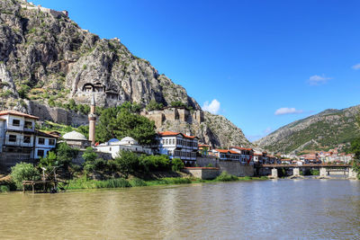 Houses by river and buildings in town against sky