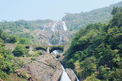 Arch bridge amidst trees and mountains against sky