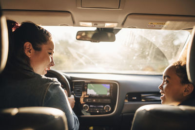 Smiling woman with daughter sitting in electric car during picnic