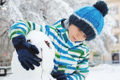 Boy making snowman in yard