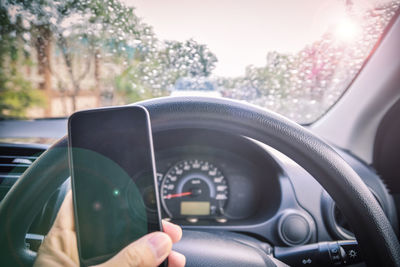 Cropped hand of person using smart phone in car