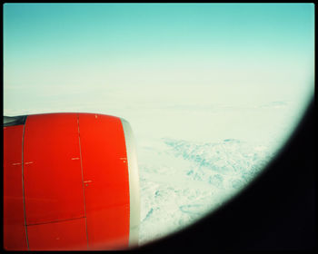 Airplane window against sky