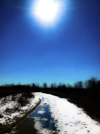 Scenic view of snow covered land against clear blue sky