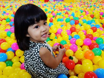 High angle view of cute smiling girl playing with colorful balls