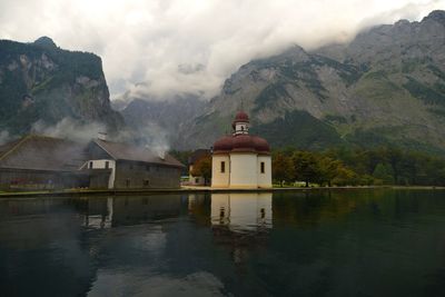 St bartholomews church by calm lake against mountain