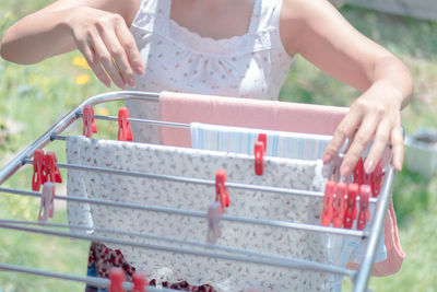 Cropped image of woman drying clothes from laundry rack