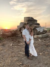 Woman standing on rock against sky during sunset