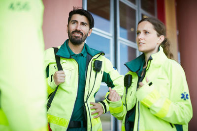 Male and female paramedics discussing while standing outside hospital