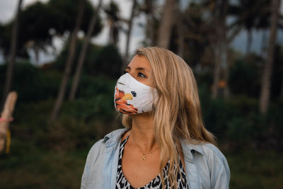 Portrait of young woman standing with mask