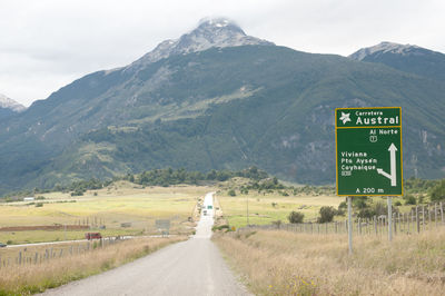 Road sign on landscape against mountain range