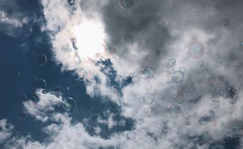 Low angle view of bubbles against cloudy sky