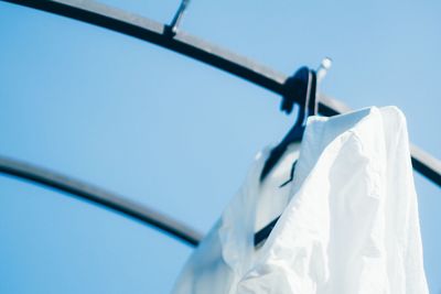 Low angle view of white shirt drying on rack against clear blue sky