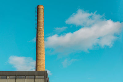 Low angle view of smoke stacks against blue sky