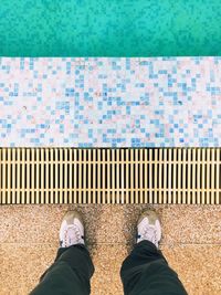 Low section of man standing by swimming pool