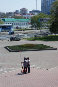 Rear view of friends on street against buildings in city