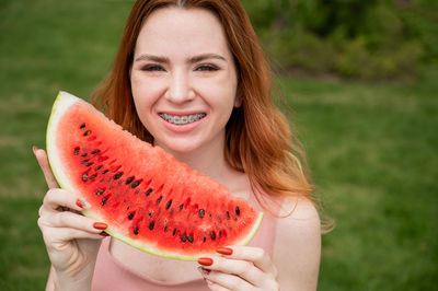 Portrait of smiling young woman holding kiwi