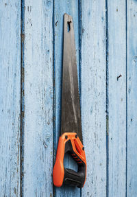 Close-up of hand saw on wooden wall