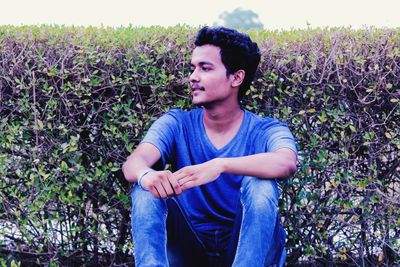 Portrait of young man sitting on field