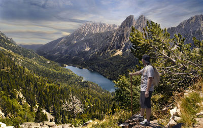 Rear view of man standing by mountain against sky