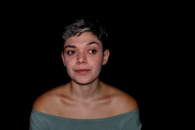 Close-up of young woman against black background