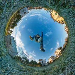 Little planet format of man jumping against sky